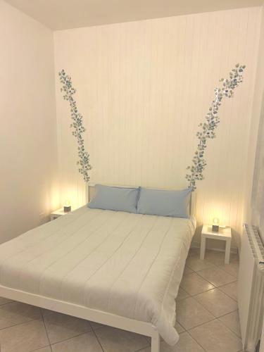 a bedroom with a bed with blue pillows and flowers on the wall at Home Sweet Home Forli in Forlì