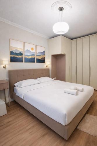 a bedroom with a large white bed and paintings on the wall at Liqeni New Apartament in Tirana