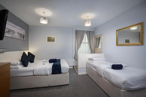 a hotel room with two beds and a mirror at Royal Oakwell Hotel in Blackpool