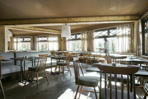 een restaurant met tafels, stoelen en ramen bij Hotel Europa in Breuil-Cervinia