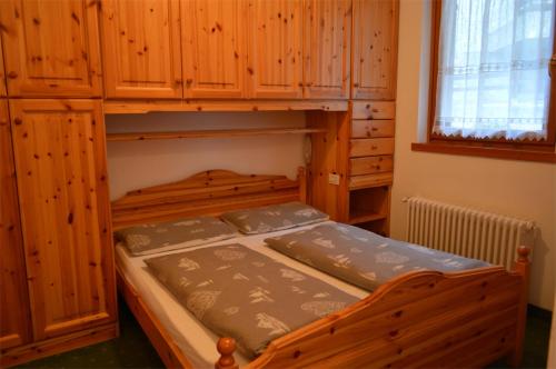 マドンナ・ディ・カンピリオにあるAppartamenti BUCANEVEの木製のキャビネット付きの客室の木製二段ベッド1台分です。
