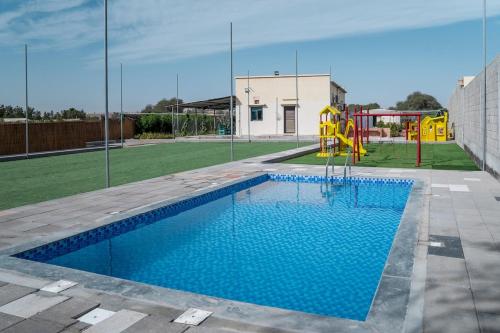 une piscine avec une aire de jeux dans une cour dans l'établissement Eco Paradise UAQ Harmony with Nature, à Umm Al Quwain