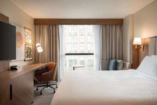 a hotel room with a bed and a desk and a window at Holiday Inn & Suites Vancouver Downtown by IHG in Vancouver