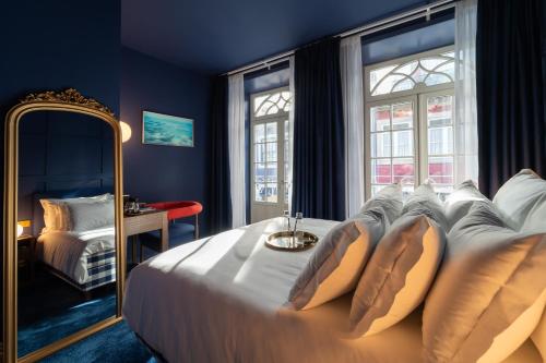 a bedroom with a large white bed with a mirror at Hotel Kodawari Flores - by Kodawari Residences in Porto