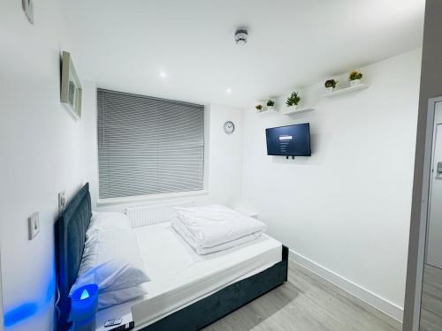a small bedroom with a bed and a tv at Letza House - Private En-Suite Rooms near Cardiff City Centre in Cardiff