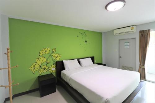 a bedroom with a white bed and a green wall at DD Residence Rayong in Rayong