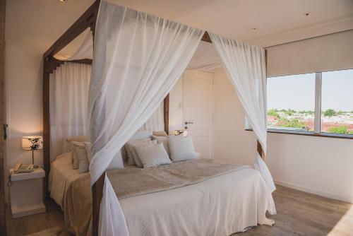 a bedroom with a canopy bed with white curtains at Los Muelles Boutique Hotel in Carmelo