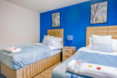 two beds in a room with blue walls at Sedgebank House in Livingston