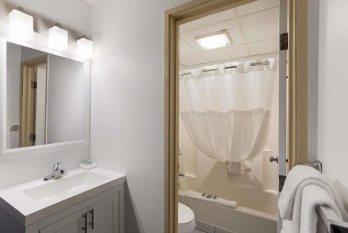 a bathroom with a sink and a toilet and a mirror at SureStay by Best Western Presque Isle in Presque Isle