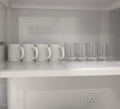 uno scaffale con una fila di tazze e una fila di bicchieri di Najd Cozy Apartment a Dammam