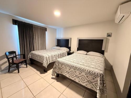 马塔莫罗斯Hotel Ossi Inn的有两张床和一把椅子的酒店房间