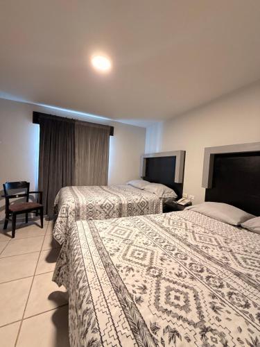 a hotel room with two beds and a chair at Hotel Ossi Inn in Matamoros