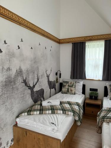 a bedroom with two beds and a wall with deer mural at Ciwersówka Domki Białka Tatrzańska in Białka Tatrzańska