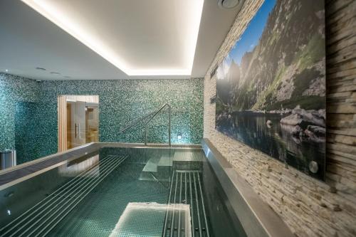 a swimming pool in a bathroom with green tiles at Apartmány Lúčny Raj in Ždiar