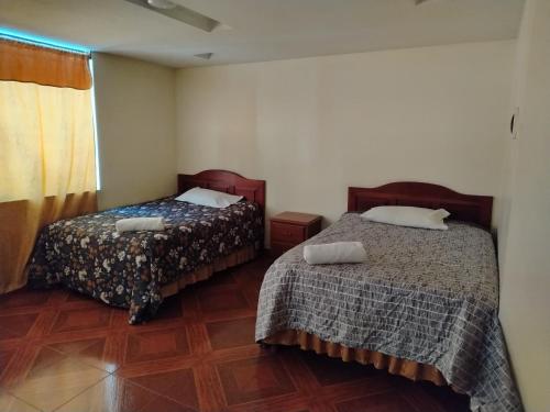 een slaapkamer met twee bedden en een houten vloer bij Asvea INN in Arequipa
