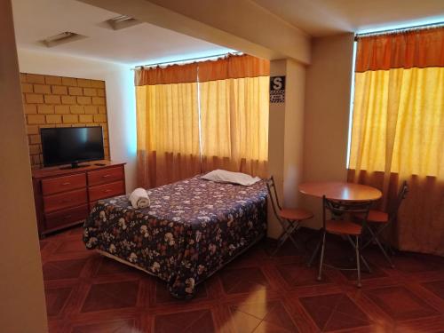 een slaapkamer met een bed, een tafel en een televisie bij Asvea INN in Arequipa