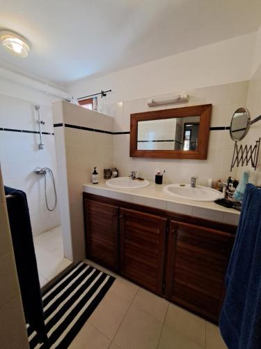a bathroom with two sinks and a shower and a mirror at 20 ' keur in Boukot Ouolof