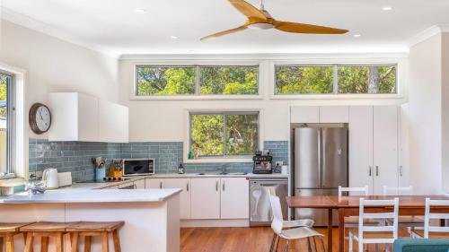 Il comprend une cuisine avec des placards blancs et un ventilateur de plafond. dans l'établissement Mountain Breeze, à Umina