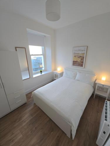 een witte slaapkamer met een wit bed en 2 lampen bij 2 Bed Apartment with Harbour Views Apt 2 in Cobh