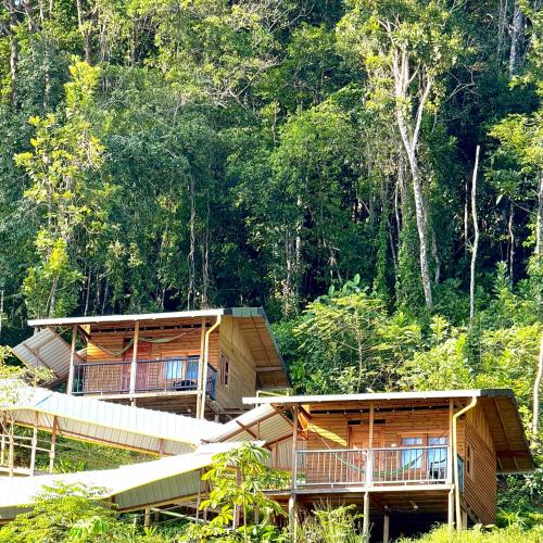 two large wooden buildings with trees in the background at Altos de la Playa in Bahía Solano