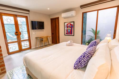 a bedroom with a large white bed and large windows at Hotel Libreria Cafe de Pombal in Santa Marta