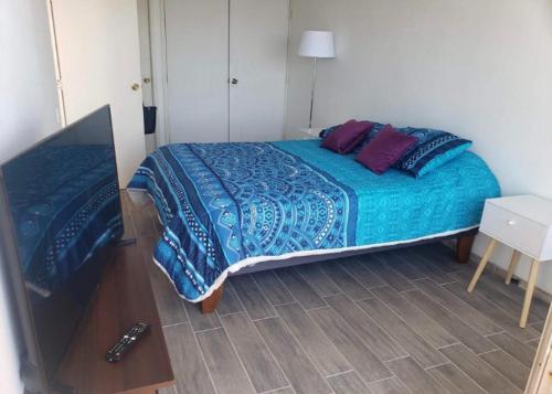 een slaapkamer met een bed met blauwe lakens en paarse kussens bij Departamento Concon Valparaíso in Concón