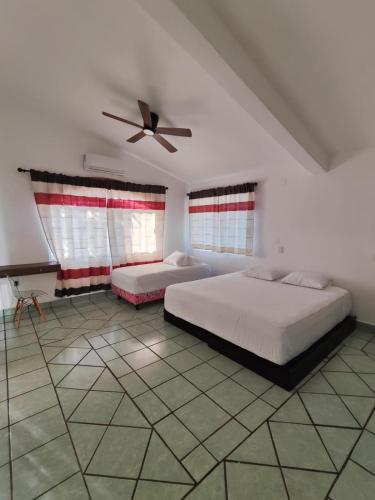 a bedroom with two beds and a ceiling fan at Casa Los Mangales in Brisas de Zicatela