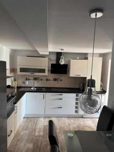 eine Küche mit weißen Schränken und einem Tisch mit Stühlen in der Unterkunft Apartament EMMA in Bistriţa