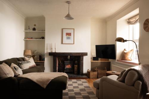 een woonkamer met een bank en een open haard bij Traditional Cornish Cottage & Garden Redruth in Redruth