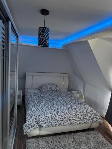 un letto in una piccola stanza con una luce blu di Apartament EMA a Bistriţa