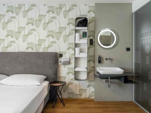 a bedroom with a bed and a sink and a mirror at ibis Styles Ljubljana Centre in Ljubljana