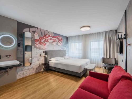 a bedroom with a bed and a red couch at ibis Styles Ljubljana Centre in Ljubljana