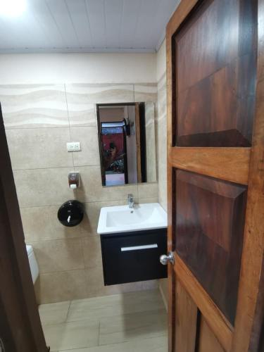 a bathroom with a sink and a wooden door at HOTEL Cabinas JACOMAR in Jacó