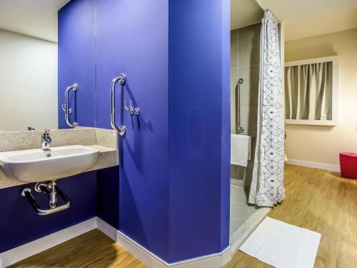 乌贝兰迪亚Ibis Budget Uberlândia的带水槽和淋浴的蓝色浴室