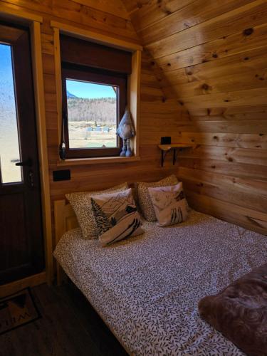 a bed in a log cabin with a window at Mountain Peace in Žabljak