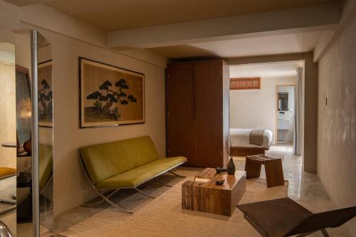 a living room with a green couch and a bed at Hotel Oculto in Mexico City