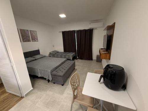 een kleine kamer met een bed, een tafel en een bank bij Flats Privativos MaragoJulios in Maragogi