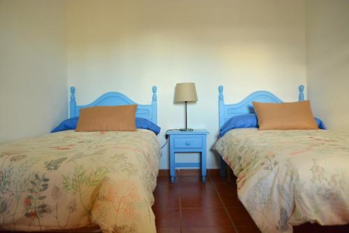 a bedroom with two beds and a table with a lamp at Casa rural en Granada in Atarfe