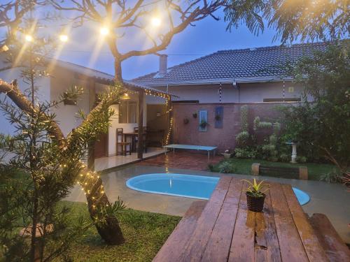 Ein Pool im Hinterhof eines Hauses mit einer Holzbank in der Unterkunft Pousada Canto das Estrelas in Chapada dos Guimarães