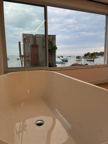 a bath tub in a room with a large window at Morada Som do Mar in Governador Celso Ramos