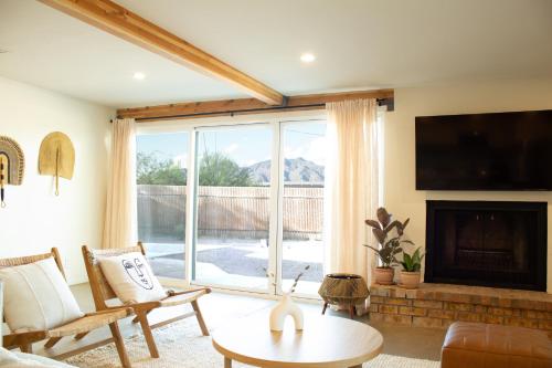 un soggiorno con camino e una grande finestra di Sonoran Peach House - 5BR Winter Retreat, Big Yard, Fireplace a Tucson