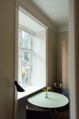 a table with a vase on it next to a window at Hotel Nora Copenhagen in Copenhagen