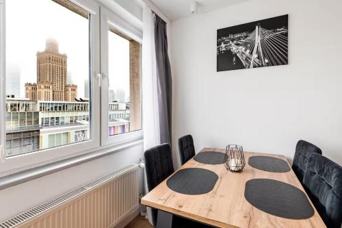 een eetkamer met een houten tafel en een raam bij Warsaw View Residance in Warschau