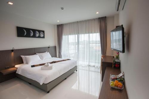 a hotel room with a bed and a television at The Elysium Residence - SHA Extra Plus in Chalong 