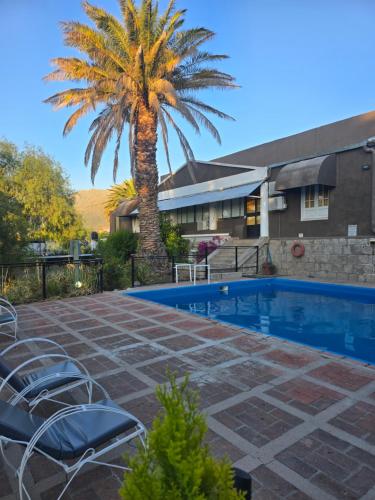 een palmboom en een zwembad voor een huis bij Hotel Uritorco in Capilla del Monte