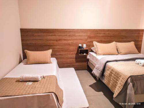 una camera con 2 letti e una parete in legno di Hotel Vale Do Ivinhema a Bataiporã