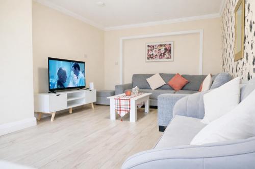 a living room with a couch and a tv at Spacious 5BR Home with Garden, Games & Parking Near Heathrow Windsor in Slough