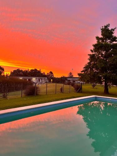 a swimming pool with a sunset in the background at Complejo Bohio Hotel Boutique in Lobos