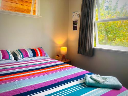 a bedroom with a colorful bed with a window at Rainbow Lodge in Motueka