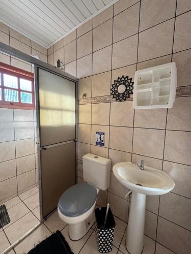 a bathroom with a toilet and a sink at Casa com piscina in Tramandaí